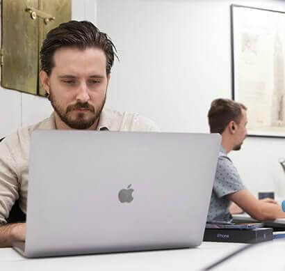 man in white chemis beard looking at his laptop in a meeting room